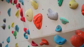 Climbing artificial rock climbing wall to practice mountain bouldering and climbing skills with colored grips and route markers for beginners. Bouldering track on simulated rock boulder walls. video