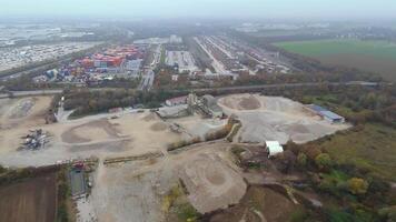 Aerial view of functioning sand quarry in industrial zone in Germany. Heavy machinery operates across sprawling sandy landscape, shrouded in autumn fog, emphasizing an active worksite atmosphere. video