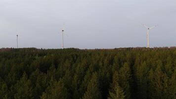 Aerial view of wind farm turbines set up in countryside with forest. Producing power using energy of nature. Incorporating technology into environment of nature. Cloudy sky. Electricity production. video