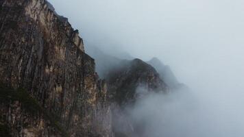 A mountain with fog and clouds in the sky photo