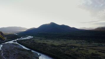 A river running through a valley with mountains in the background photo