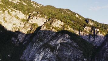A stone mountain slope overgrown with a dense forest in the light of the rising sun, shot from a bird's eye view from a quadrocopter. Rocky mountain slopes close-up from drone photo