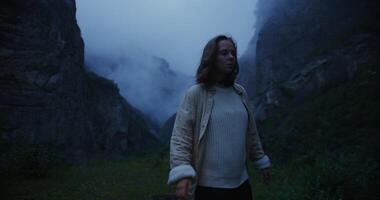 A woman standing in front of a mountain with fog photo