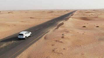 A car drives through the desert in the middle of the day photo