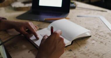 A person is writing on a notebook with a pencil photo