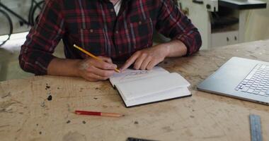 A man sitting at a table writing in a notebook photo