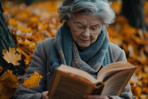 An older woman reading a book in the fall photo