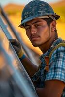 A young man in a hard hat and overalls is leaning against a metal wall photo