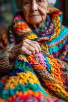 An elderly woman is knitting a colorful knitted blanket photo