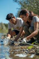 Two people kneeling down to collect water from a river photo