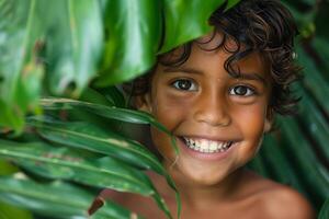 A young boy smiles through leaves in the jungle photo