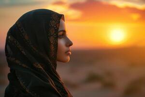 A woman in a headscarf looking at the sunset photo