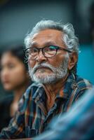 An old man with glasses and a beard sitting at a table photo