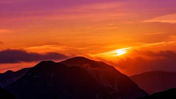 Scenic sunset over the mountain range peaks and summit with colorful magenta clouds photo