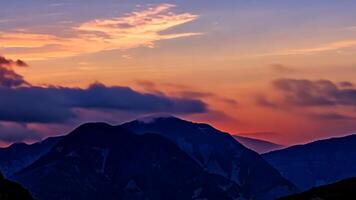 Scenic sunset over the mountain peaks and summit with colorful magenta and orange clouds photo