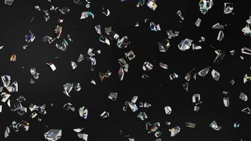Small crystal shards are scattered on a black background, reflecting light and sparkling with colors, showing slow motion video