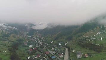 Mountain village with small river with fog and mist. Village environment, changing weather in city, scenery green landscape hiking video