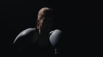 A boxer boxing with shadows in a semi-dark room with flashlights behind him, slow motion footage video