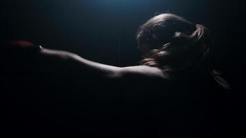Silhouette with backlit female fighter practicing quick strikes shadow boxing fight video
