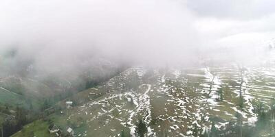 Top of view to mountain village and foggy green field, morning environment, mist-covered seasonal, landscape natural meadow, mist and green field, pieces of snow and greenery video