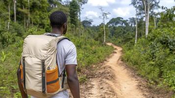 Man Hiking on Dirt Trail Through Lush Green Forest photo