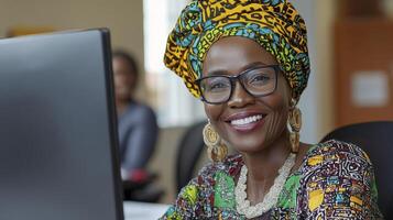 Smiling Woman in Colorful Headwrap Working at Computer photo