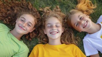 Smiling Girls with Curly Hair Lying on Green Grass photo