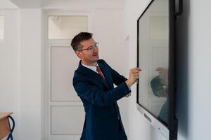 University male teacher giving lecture in the classroom or business man presenter public speaking in a conference meeting room using a display screen board. . photo