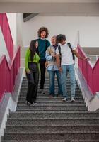 A group of happy diverse college students hanging out they are talking with each other while walking in the university hallway. photo