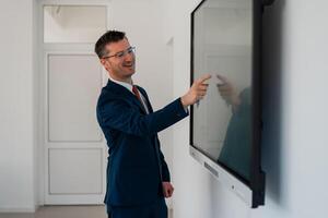 University male teacher giving a lecture in the classroom or a happy business man presenter public speaking about a working plan and strategy in a conference meeting room using a display screen board. photo