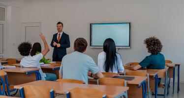 In the classroom group of college students listening to a university lecturer and engages in discussion and debate. Student raising a hand with a question for the teacher. photo