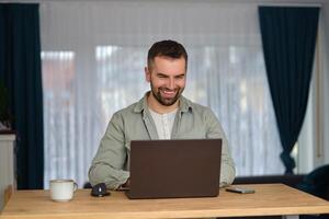 A happy man using a laptop while working at home office. photo