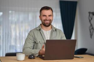 A happy man using a laptop while working at home office. photo