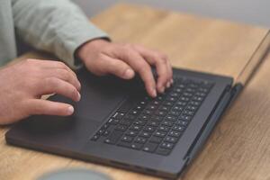 Closeup image of a business man hands working and typing on laptop keyboard on the wooden desk table. photo
