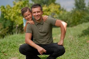 Portrait of a happy young father and son in the summer park. photo