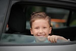 Happy kid boy looking out the car window. photo