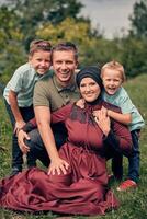 Portrait of a happy Muslim family, young mother and father with two child in the summer park, looking at the camera and smiling.. photo