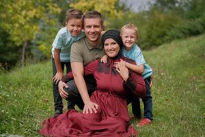 Portrait of a happy Muslim family, young mother and father with two child in the summer park, looking at the camera and smiling.. photo
