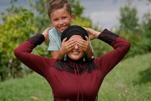 Happy Muslim family having fun together, mother and child playing in summer park. photo