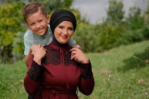 Portrait of happy Muslim family outside, mom and child son hug with love in summer park, looking at the camera and smiling.. photo