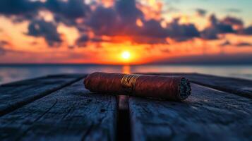 A cigar laying on a wooden table with the sun setting in the background photo