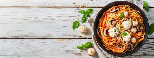 Spaghetti with mushrooms and tomatoes in a black pan on a white wooden table top view photo
