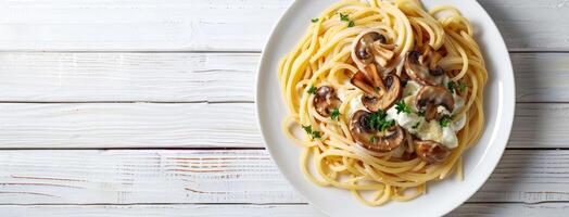 Spaghetti with mushrooms and cream sauce on white wooden table photo