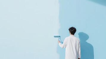 A man is painting a blue wall with a paint roller photo