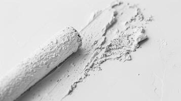 A white paint brush is laying on a white surface photo