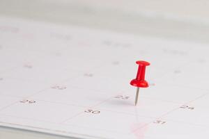 red push pin on calendar page background photo
