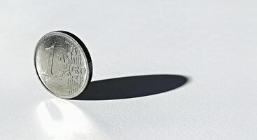 A coin sitting on a table with a shadow photo