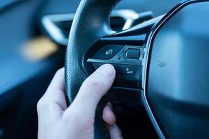 Close-up of a hand pressing the voice command button on a steering wheel, showcasing smart car technology, AI-driven assistance, and hands-free driving innovation photo