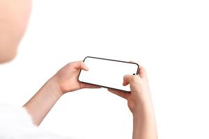 Boy holds a smartphone in a gaming position, using both thumbs on the screen. Over-the-shoulder view, isolated display and background, perfect for game promotion photo