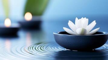 White lotus flower floating in a bowl with candles in background photo